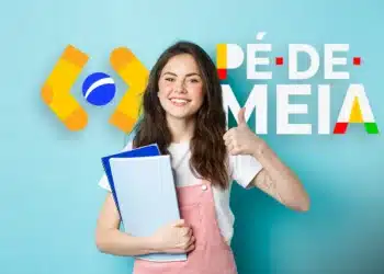 Jovem sorridente segurando cadernos e mostrando sinal de positivo, com logo do programa Pé de Meia ao fundo.