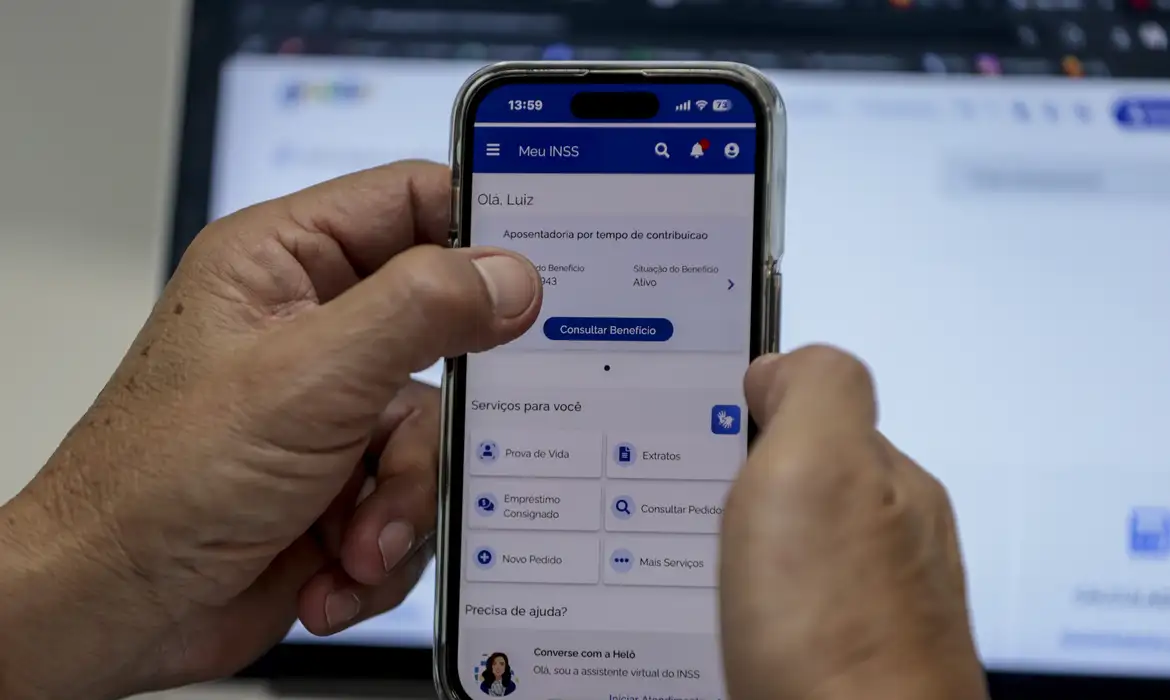 Acesso ao Meu INSS pelo aplicativo móvel Pessoa segurando celular e usando o aplicativo Meu INSS para consultar benefícios.