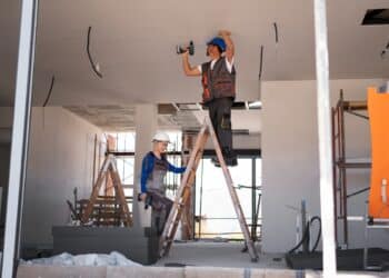 Trabalhadores realizando reforma em construção civil com equipamentos profissionais