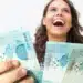 Empréstimo rápido e sem burocracia: Como conseguir dinheiro na hora 11 Mulher jovem e feliz segurando várias notas de cem reais, simbolizando a alegria de conseguir dinheiro rápido.