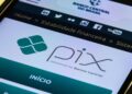 Tela de celular exibindo o logo oficial do Pix "powered by Banco Central" no site da instituição, simbolizando a notícia sobre o adiamento do lançamento do Pix Parcelado por questões de segurança contra fraudes e golpes milionários.