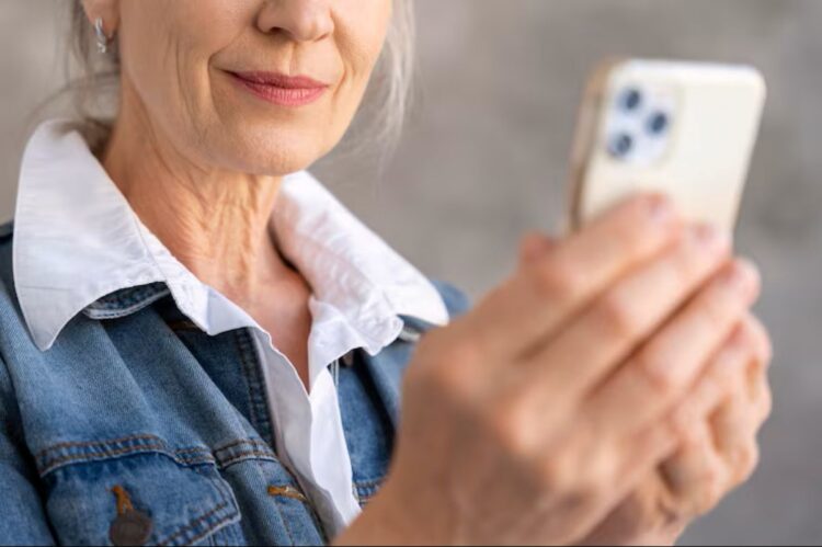 Mulher sênior sorrindo enquanto usa o celular, representando a facilidade da Prova de Vida digital para aposentados.
