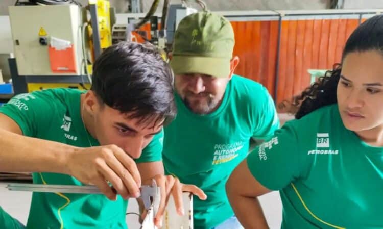 Jovens e adultos participando de uma atividade prática ou treinamento profissional em uma oficina, com o logo da Petrobras em suas camisetas, simbolizando qualificação e autonomia.