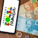Novidade no app do Bolsa Família: veja o valor confirmado da parcela de outubro 11 Smartphone com logo do Programa Bolsa Família ao lado de cédulas e moedas brasileiras sobre mesa de madeira