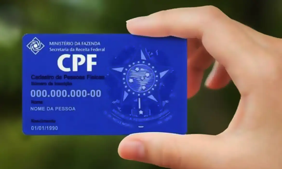 Mão segurando carteira de CPF digital azul com informações fictícias em fundo desfocado verde CPF