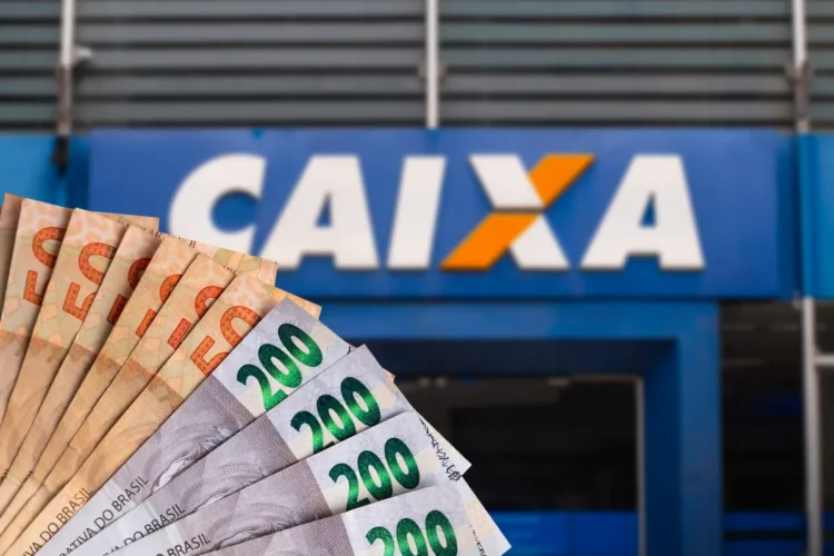 Dinheiro em notas de reais em frente a agência da Caixa Econômica Federal