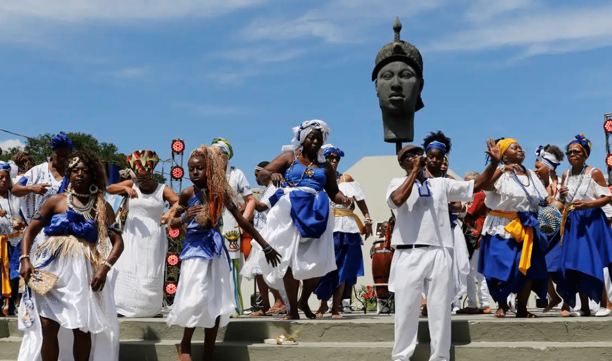 Celebração do Dia da Consciência Negra com pessoas em trajes tradicionais e monumentos culturais.