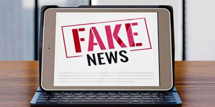 Tablet com a frase 'FAKE NEWS' em carimbo vermelho e preto, desmentindo a informação de R$ 5 mil para mães do Bolsa Família.