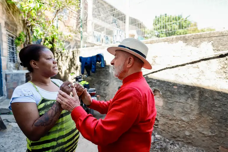 Pessoas dançando ao ar livre na favela Homem idoso de chapéu e mulher sorridente dançando juntos em área externa de favela