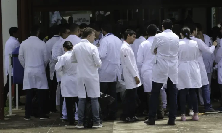 Grupo de médicos com jalecos brancos reunidos na entrada da sala de espera de hospital ou clínica