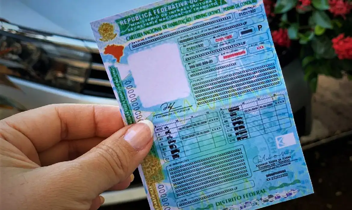 Benefícios CNH Social Mão-segurando-a-nova-Carteira-Nacional-de-Habilitação-CNH-representando-a-conquista-do-documento-por-meio-da-CNH-Social