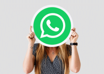 Mulher com cabelo longo segurando placa com símbolo verde do WhatsApp cobrindo o rosto