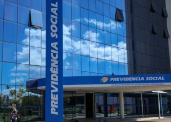 Prédio sede do Instituto Nacional do Seguro Social INSS em Brasília, fachada moderna de vidro azul com o banner de "Previdência Social"