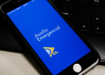 Tela de smartphone mostrando o aplicativo Auxílio Emergencial aberto em fundo azul com símbolo amarelo