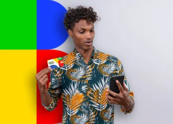 Homem segurando cartão de benefícios com design colorido e usando um celular preto