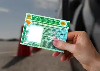 Mão segurando a Carteira Nacional de Habilitação (CNH) em formato físico, representando novas regras de trânsito.