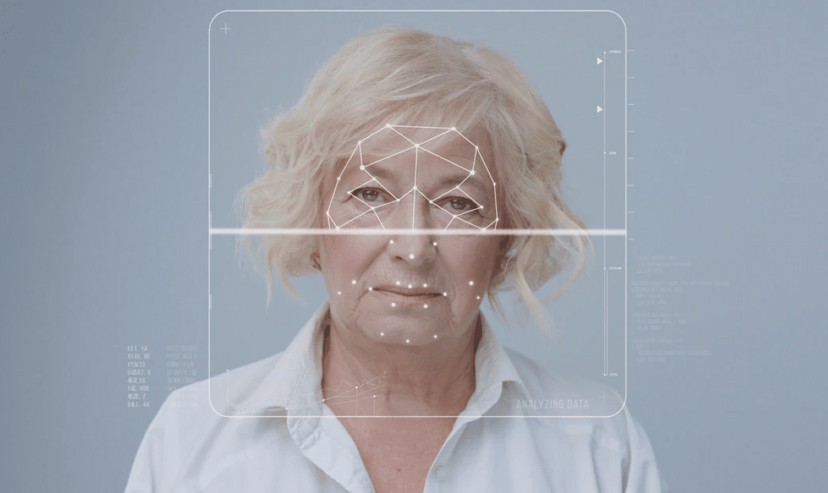 Rosto de uma mulher sênior sob escaneamento facial com gráficos digitais, ilustrando a prevenção de fraudes por biometria no empréstimo consignado.