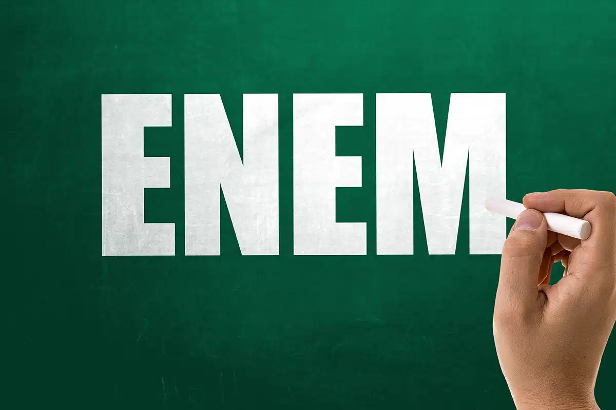 ENEM: Exame Nacional do Ensino Médio A palavra "ENEM" escrita em branco com giz em um quadro verde escuro, simbolizando a importância do exame para o acesso ao ensino superior e a obtenção do incentivo do Pé-de-Meia.