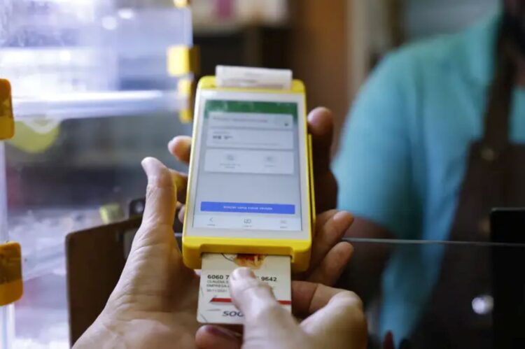 Pessoa inserindo cartão em dispositivo amarelo de pagamento digital com tela touch