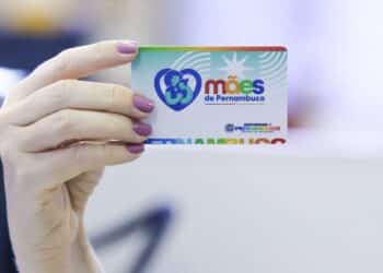 Mulher segura o Cartão Mães de Pernambuco, benefício social de R$ 300 para mães em vulnerabilidade.