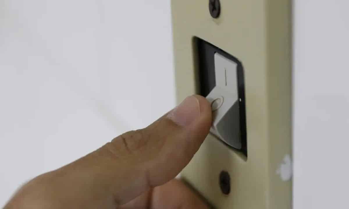 Dedo de uma pessoa pressionando um interruptor de luz, simbolizando o ato de economizar energia elétrica.