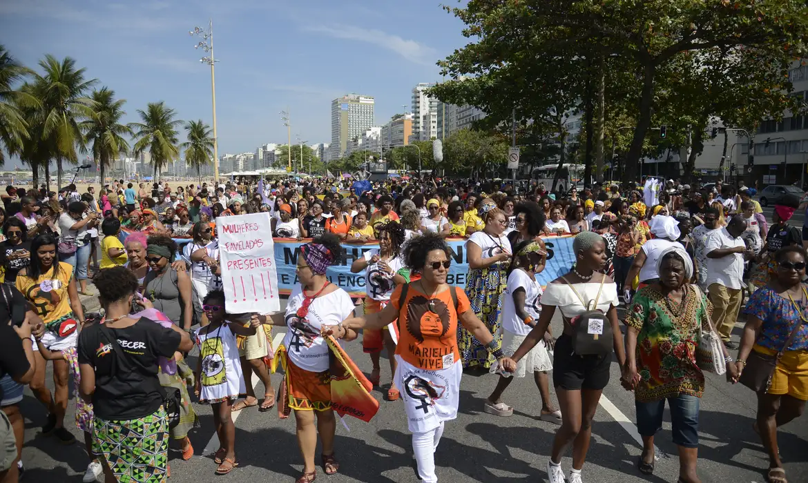 Marcha de Mulheres Negras no Rio de Janeiro Multidão de mulheres negras na Marcha em Copacabana segurando cartazes e mãos dadas