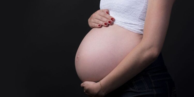 Imagem de uma gestante com a mão sobre a barriga, ilustrando o procedimento obrigatório para manter o Bolsa Família.