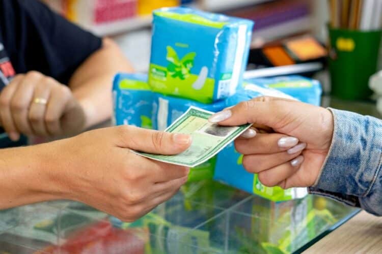 Estudante retirando absorventes gratuitamente em farmácia credenciada ao Programa Dignidade Menstrual.