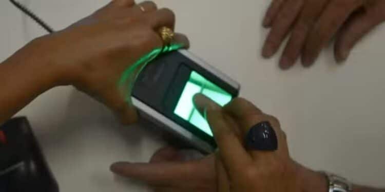 Pessoa realizando coleta de digitais em equipamento biométrico durante atendimento público.