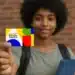 Adolescentes do Bolsa Família: mais de 100 mil perdem benefício extra por faltas escolares 11 Jovem segurando cartão colorido do Programa Bolsa Família com foco no cartão.