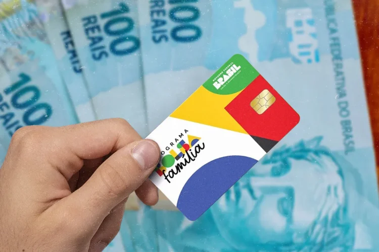 Beneficiários de NIS final 3 recebem Bolsa Família nesta sexta (12) 1 Imagem de uma mão segurando o cartão do Programa Bolsa Família com notas de 100 reais ao fundo, representando o pagamento do benefício.