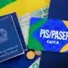 Saiu o calendário do PIS/PASEP 2026: Confira seu mês de pagamento 11 Carteira de trabalho, dinheiro em reais e cartão PIS/PASEP Caixa sobre bandeira do Brasil