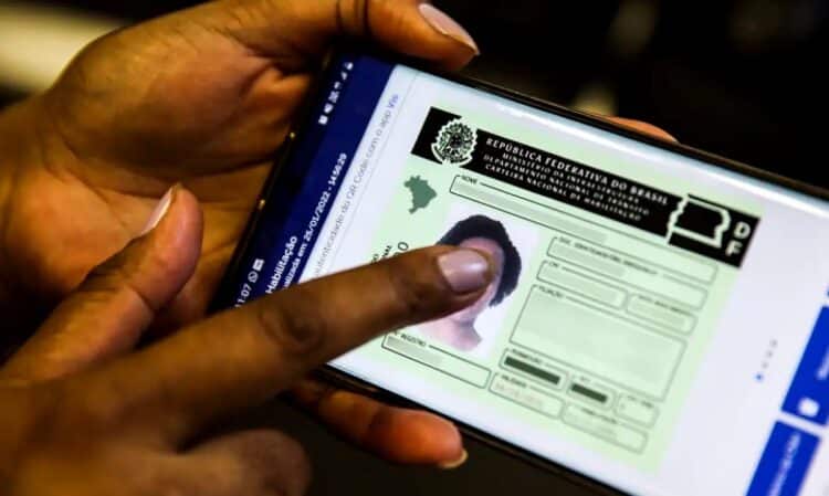 Pessoa utilizando um smartphone para visualizar a Carteira Nacional de Habilitação (CNH) Digital, ilustrando a modernização das regras e o uso de aplicativos para acesso a informações e aulas gratuitas.
