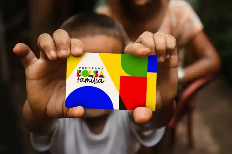 bolsa familia Criança segurando cartão colorido do Bolsa Família em 2026.
