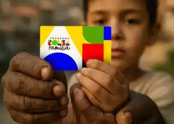 Mãos de um adulto e uma criança segurando o cartão do Programa Bolsa Família.