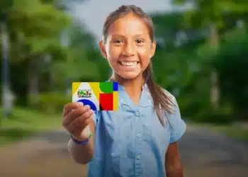 O sorriso de uma criança segurando um cartão do programa Bolsa Família.