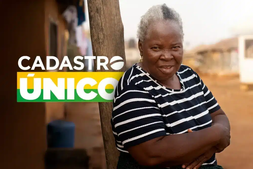 Cadastro Único - Identificação de famílias em situação de vulnerabilidade Idosa sorrindo em um ambiente comunitário, com o logo do Cadastro Único ao fundo.