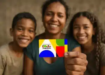 Mãe e filhos sorrindo enquanto seguram o cartão do Bolsa Família.