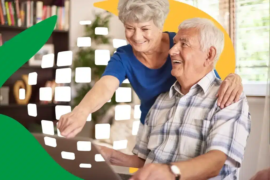 Inss e novas exigências. Casal de idosos sorrindo e interagindo com um laptop, ilustrando o uso da tecnologia para acessar serviços do INSS.
