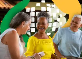 Pessoas sorrindo em um encontro social com fundo colorido, destacando a alegria e a interação entre beneficiários do INSS.