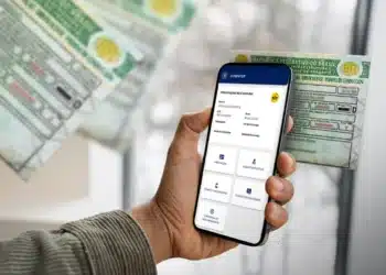 Pessoa acessando renovação automática da CNH no celular ao lado da CNH física.