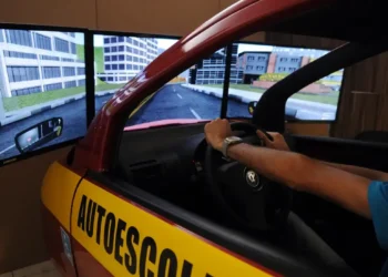 Simulador de direção para aulas de autoescola com tela panorâmica e volante.