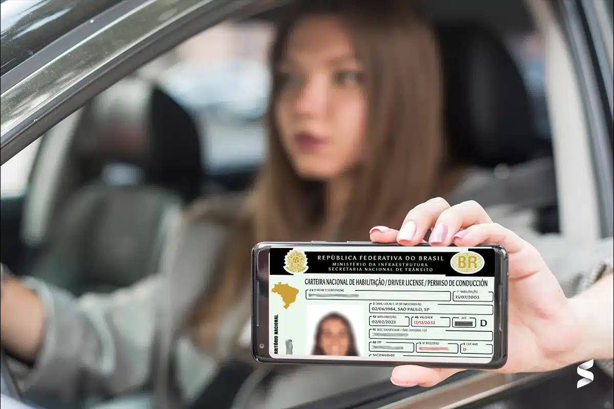 CNH digital exibida no celular por motorista dentro do carro Motorista segura celular com carteira de habilitação digital visível na tela e rosto desfocado ao fundo