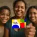 Bolsa Família: o que é verdade e o que é mentira sobre mudanças no pagamento em 2026 11 Mulher segura cartão colorido do Bolsa Família com duas crianças sorrindo ao fundo