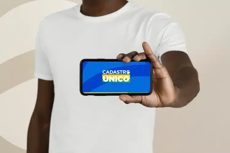 CadÚnico sai do ar por 4 dias e trava serviços em todo o país 1 Pessoa segura smartphone exibindo logo do Cadastro Único em destaque.