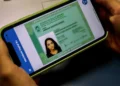 Carteira de identidade gratuita e digital — saiba como garantir a sua 4 Mãos seguram smartphone mostrando RG digital na tela