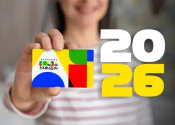 Mulher segurando cartão colorido do Bolsa Família com números 2026 ao fundo.