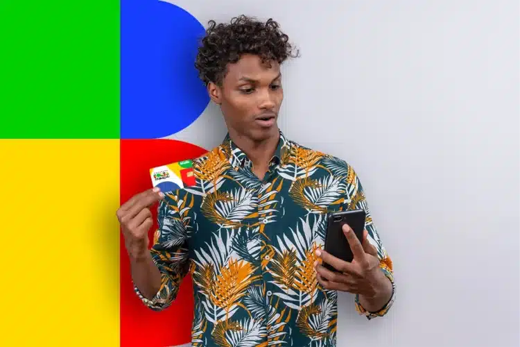Quando cai o Bolsa Família em maio de 2026? Confira o calendário oficial completo 2 Homem negro com camisa estampada tropical segura cartão Bolsa Família na mão direita e celular na esquerda.