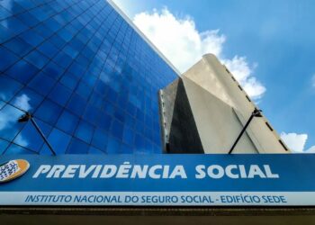 Fachada da Previdência Social com prédio moderno espelhado ao fundo