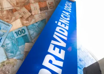 Justiça libera R$ 2,7 bilhões do INSS: veja quem pode sacar e como consultar 5 Notas de real sobre placa azul da Previdência Social, simbolizando liberação bilionária do INSS.